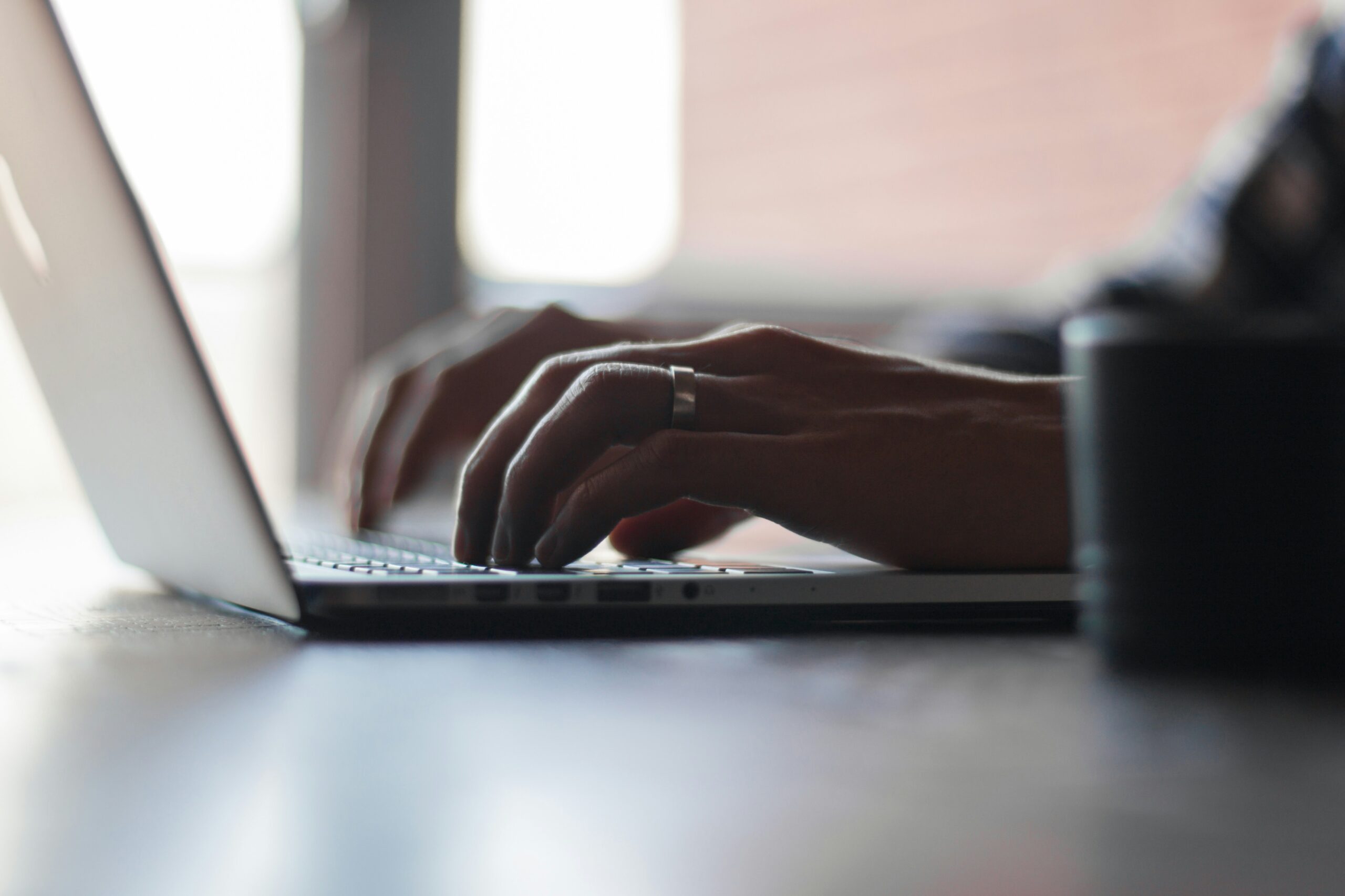 woman with wedding ring typing on computer