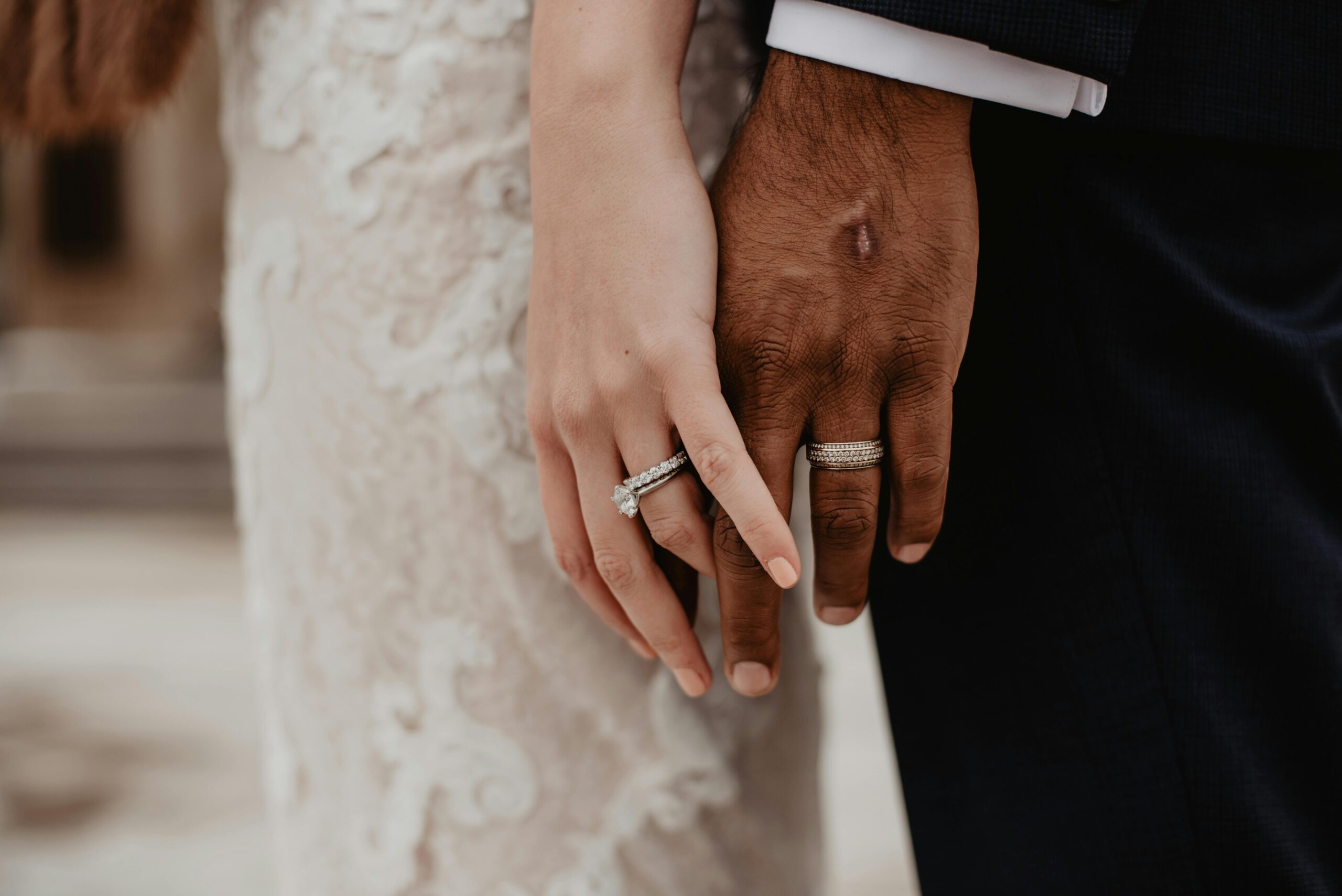 husband and wife in wedding dress but only hands with rings in image